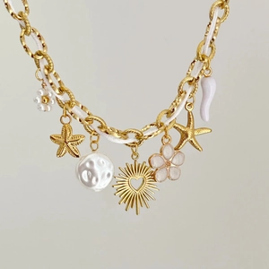 Détail du collier chaîne dorée avec perle baroque, breloques étoile de mer et corde tressée