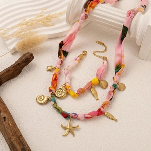 Détail du collier bohème en tissu floral avec pendentifs en coquillages dorés et étoiles