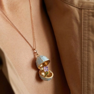 Detail of egg-shaped enamel pendant opening to reveal an intricate purple flower