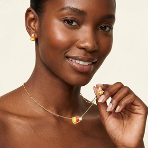 Feestelijke candy corn sieradenset met gouden ketting en oorbellen op een model