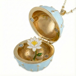 Detail of light blue enamel Fabergé style egg pendant opening to reveal a white lotus flower