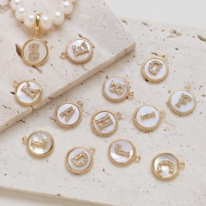 Detailed shot of gold-plated alphabet charms with zircon inlay and mother of pearl