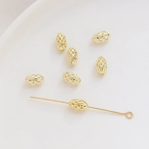 Detalle macro de cuentas ovales de malla hueca bañadas en oro 14K para accesorios de joyería