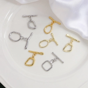 Close-up of gold and silver toggle clasps for DIY jewelry making on white silk