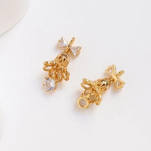 Detailed close-up of 14k gold plated Christmas bell charms with bowknot and zircon insets