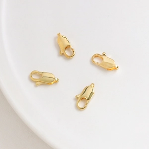 Macro view of 4 pieces 14K gold plated lobster clasps on a white ceramic plate