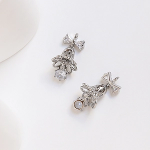 Macro shot of silver bow bell earrings with zircons and a large round cut crystal drop