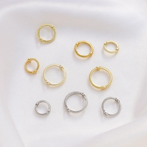 Detalle de aros con textura bañados en oro de 14K sobre una elegante tela de seda blanca