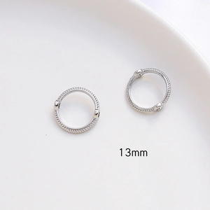 Detalle macro de anillos redondos plateados 13mm textura cuerda con dos agujeros de conexión