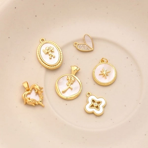 Macro detail of six gold-plated rose and angel mother of pearl charms with zircon accents