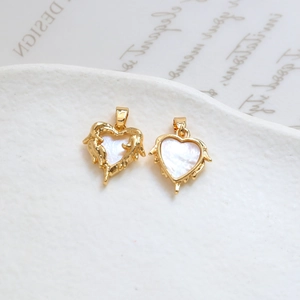Macro detail of heart shaped gold pendants with white shell inlay and lava texture