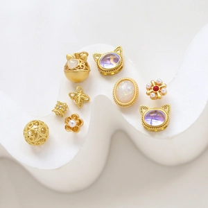 Colección de dijes dorados con forma de gato y cuentas con relieve en bandeja blanca