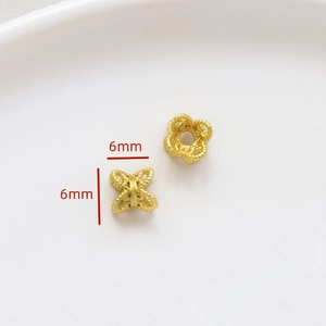 Vista macro de dos cuentas de flores huecas doradas de 6mm para crear joyas DIY