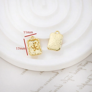 Macro view of 11x17mm gold rectangular pendants with butterfly and hammered textures