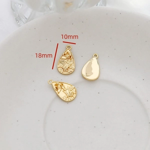 Detail view of 18x10mm gold lotus embossed water drop charm with a glossy back finish