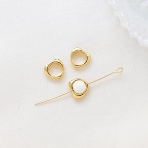Macro detail of 14k gold-plated heart spacer beads with white pearl for DIY jewelry