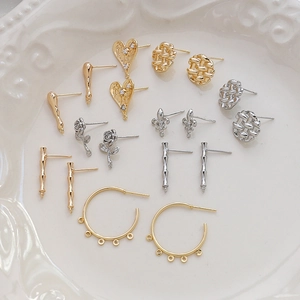 Gold-plated vintage earring hooks and charms with zircon inlays on a white ceramic plate