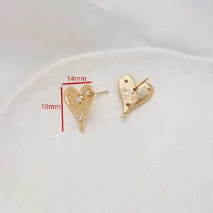 Detailed view of heart-shaped gold earring finding with zircon and hammered texture