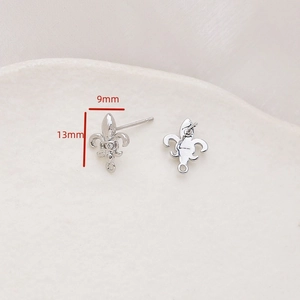 Macro detail of silver fleur-de-lis earring charms with zircon center and hanging loop