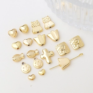 Perles dorées pour bijoux DIY en formes de cœur, chat et fleur sur fond blanc