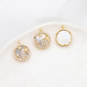 Macro detail of gold plated charms with white mother of pearl and crystal inlay