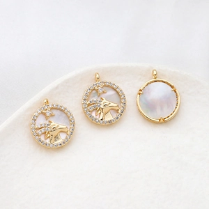 Detail of gold-plated Capricorn zodiac pendants with white mother of pearl and zircon stones