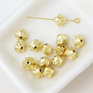 Detailed macro view of gold-plated flower-shaped irregular textured spacer beads for DIY jewelry