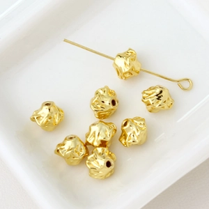 Macro detail of irregular gold-plated flower spacer beads with textured metal finish