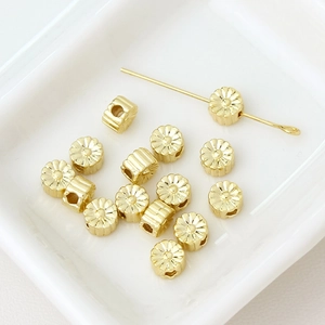 Macro detail of gold flower spacer beads on ceramic tray for DIY jewelry making