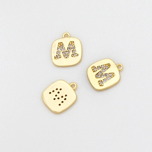 Makro-Detail von vergoldetem quadratischem M-Anhänger mit glitzerndem Zirkonia-Inlay