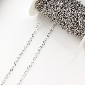 Détail d'une chaîne à maillons en forme de cœur argenté sur bobine pour création bijoux