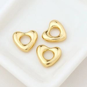 Macro detail of three 18k gold plated hollow heart pendants for DIY jewelry making