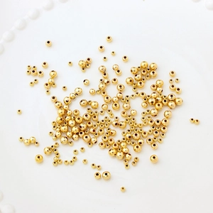 Makroaufnahme von 14K vergoldeten Rundperlen für DIY-Schmuck auf weißer Keramik