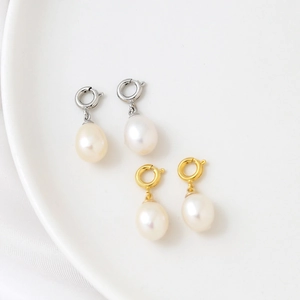 Elegant teardrop freshwater pearl earrings with gold and silver spring clasps on porcelain