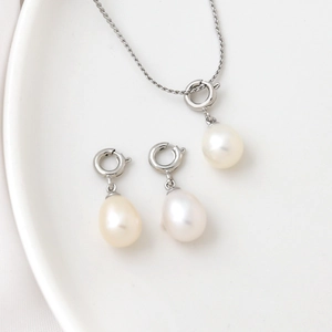 Detailed macro view of 18K natural freshwater pearl pendants and chain on white tray