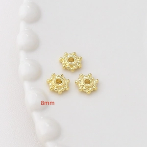 Dettaglio macro di distanziatori a fiore placcati oro 8mm per creazione gioielli