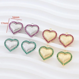 Macro detail of 16mm heart charms with red and green stones and gold-plated finish