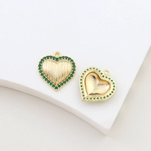 Detailed macro view of heart charm with gold plating and inlaid green zircon stones