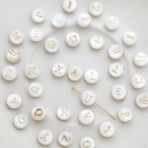 Detailed view of 8mm natural shell alphabet beads with gold finish letters for DIY jewelry
