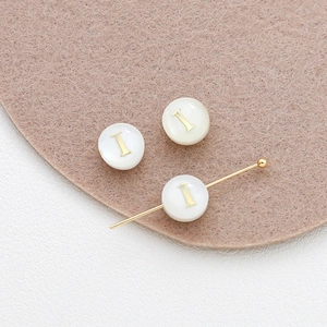 Macro shot of 8mm natural shell alphabet beads with gold letter I for DIY jewelry