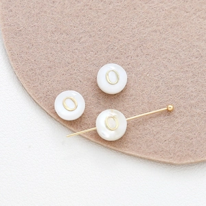 Close-up of 8mm shell beads with gold letter O for DIY bracelet jewelry making