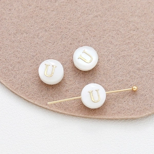 Detail of 8mm shell-texture bead with gold letter U and functional horizontal hole