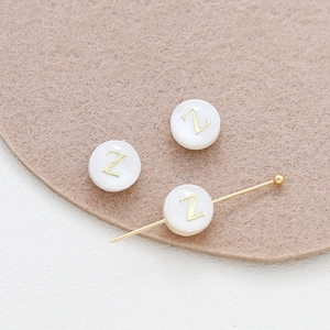 Macro shot of 8mm natural shell round beads with golden letter Z for DIY jewelry making