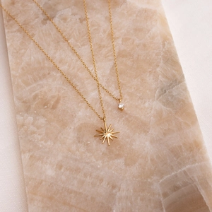 Detailed view of layered 18K gold plated titanium star and zircon pendant necklaces