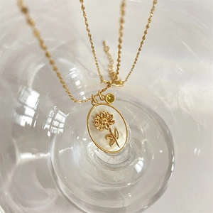Detalle del collar con colgante de girasol en nácar blanco y circón amarillo fino