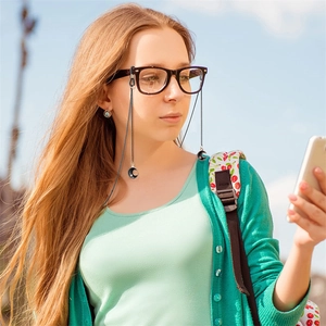 Elegant black eyewear chain set with moon charms worn by model in sunny outdoor setting