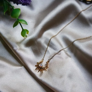 Golden sun and moon opal necklace on elegant silk background with floral accents