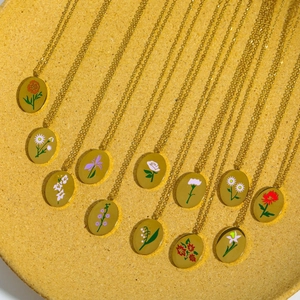 Collection de colliers à pendentifs floraux ovales dorés sur plateau en céramique