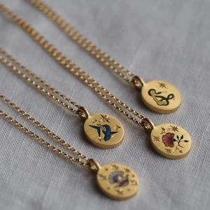 Detail of vintage-style gold plated oval pendants featuring diverse hand-painted floral motifs