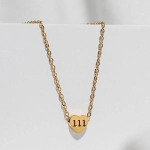 Detailed close-up of golden heart pendant with engraved 111 angel number on O-chain
